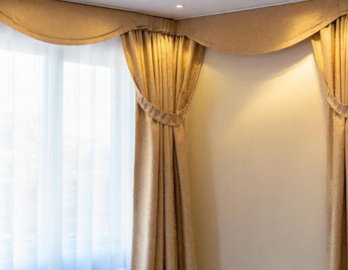 Elegant golden curtains drape beside a soft, sheer white curtain in a bright room.