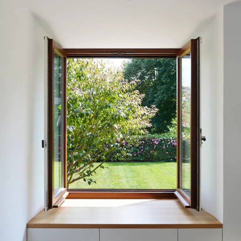 Wooden windows open to a lush garden with greenery and blooming flowers.