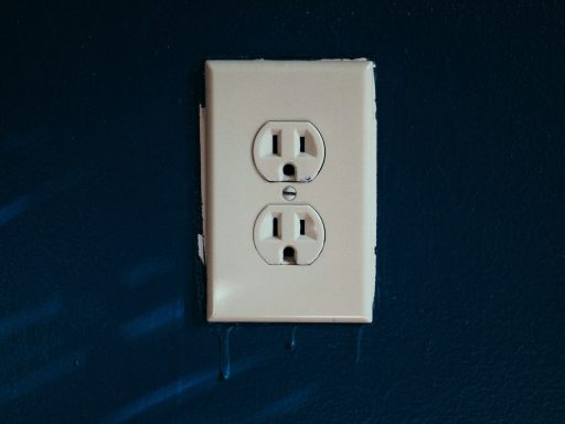 White electrical outlet on a blue wall with small water drips below.