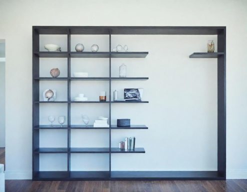 Modern black shelving unit displaying various decorative items and books against a white wall.