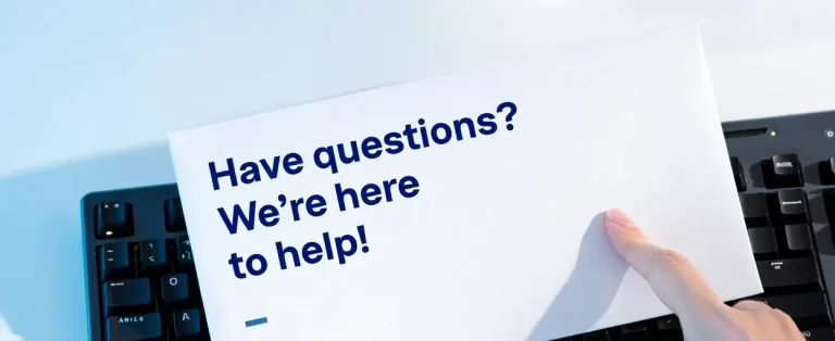 Hand holding a card that reads, "Have questions? We're here to help!"