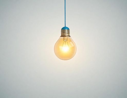 A glowing light bulb hangs from a blue cord against a plain background.